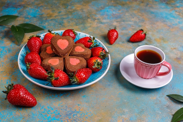 Galletas de chocolate y fresa en forma de corazón con fresas frescas, vista superior