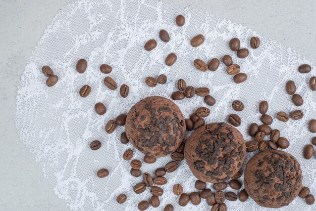 Galletas de chocolate con granos de café sobre superficie blanca