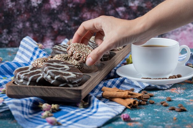 Galletas de chocolate con sésamo servidas con una taza de bebida.