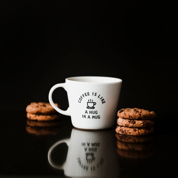 Foto gratuita galletas de chocolate y taza de cerámica sobre fondo negro