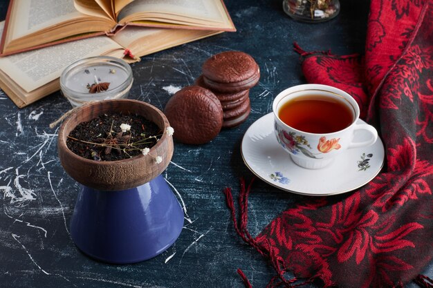 Galletas de chocolate en una taza de madera con una taza de té.