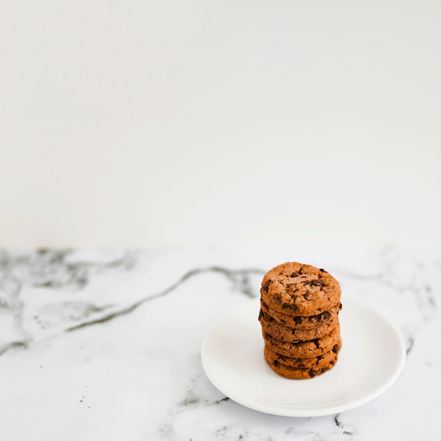 Las galletas cocidas al horno apilan en la placa blanca sobre el contexto de mármol