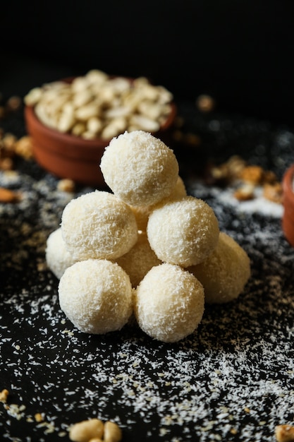 Galletas de coco vista frontal con copos de coco y nueces sobre fondo negro