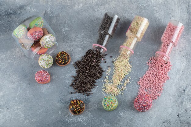 Galletas de colores con caramelos en frasco de vidrio con montón de chispitas.