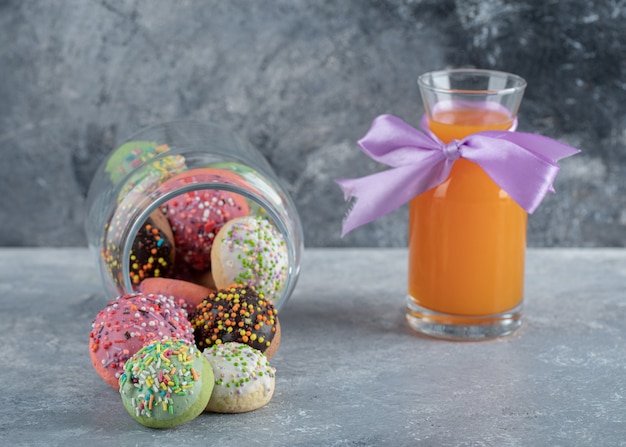 Foto gratuita galletas de colores con chispitas en frasco de vidrio y jugo de naranja.j