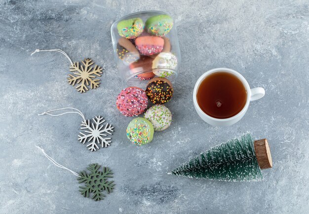 Galletas de colores, pino y té en la mesa de mármol.