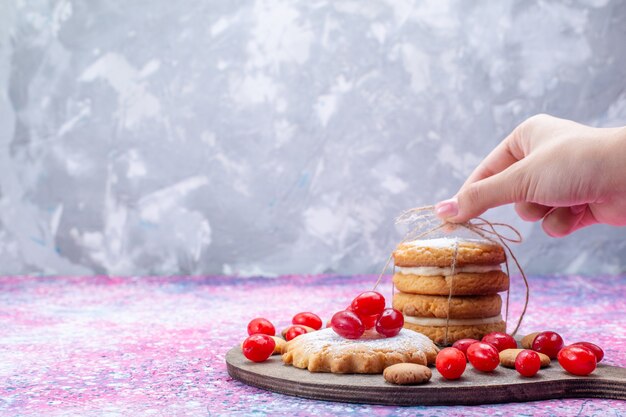 Galletas cremosas tipo sándwich con cornejos rojos sobre un pastel de galleta brillante, una galleta, una fruta agridulce, una baya