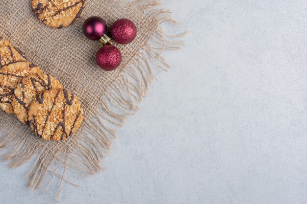 Galletas crujientes y adornos navideños sobre un trozo de tela sobre la superficie de mármol