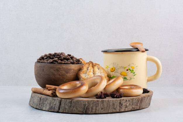 Galletas, cuenco de granos de café y taza en pieza de madera