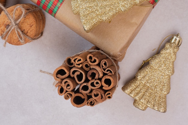 Galletas en cuerda con canela y juguete de Navidad sobre superficie blanca