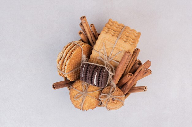 Galletas en cuerda con ramas de canela sobre superficie blanca