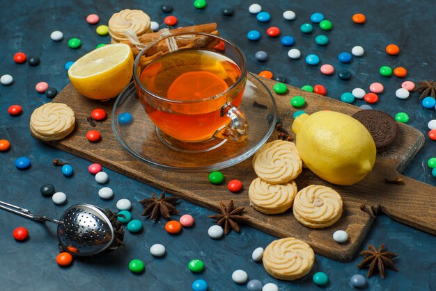 Galletas con dulces, especias, té, limón vista de ángulo alto en estuco y tabla de cortar