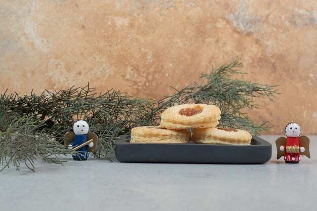 Galletas dulces con mermelada en tablero oscuro y juguetes