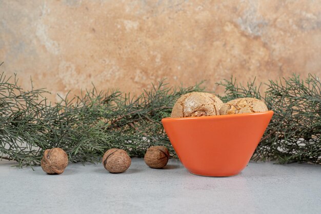 Galletas dulces redondas con nueces sobre superficie blanca.