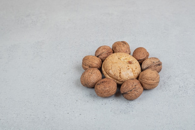 Galletas dulces redondas con nueces sobre superficie blanca