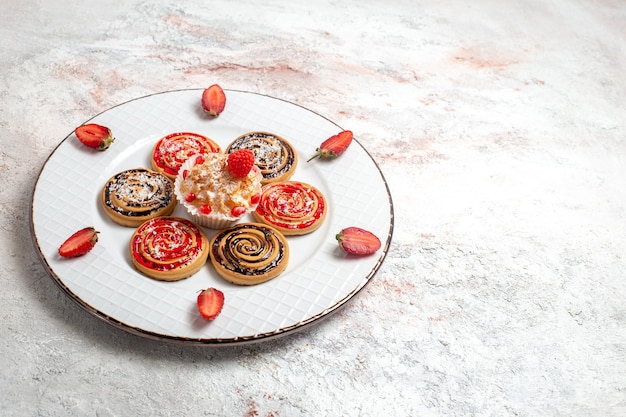 Foto gratuita galletas dulces de vista frontal con pastelito y fresas en el espacio en blanco