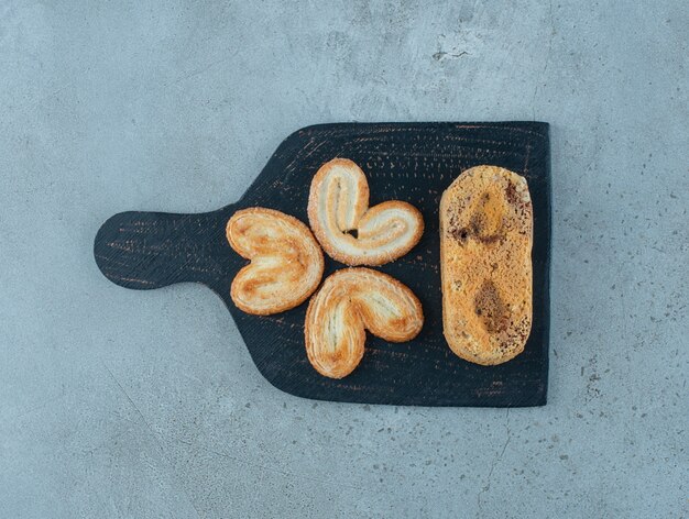 Galletas escamosas y un pequeño pastel en una tabla sobre fondo de mármol. Foto de alta calidad