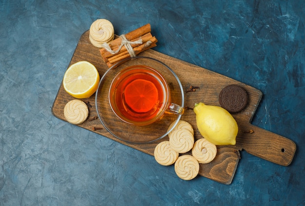 Galletas con especias, té, limón vista superior en azul oscuro y tabla de cortar