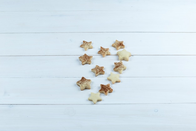 Galletas de estrella sobre un fondo de tablero de madera blanca. vista de ángulo alto.