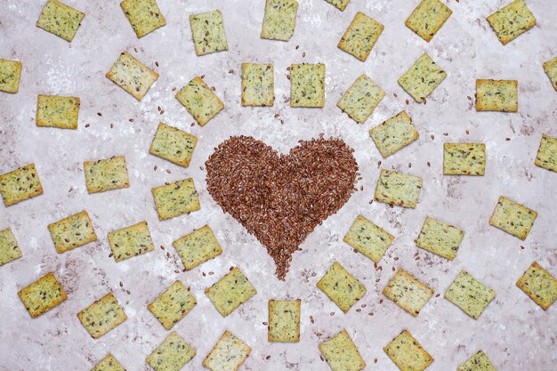 Galletas en forma de corazón de semillas de lino con aceite de oliva, semillas de lino y verduras, vista superior