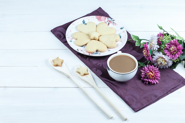 Galletas en forma de corazón de vista de ángulo alto, taza de café en mantel púrpura con flores