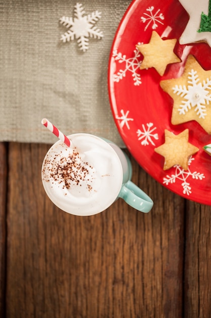 Galletas con forma de estrella sobre un plato rojo y una taza con nata