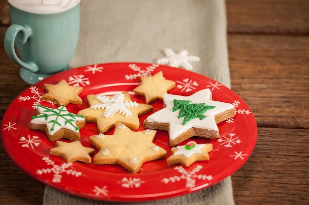 Galletas con forma de estrella sobre un plato rojo y una taza con nata