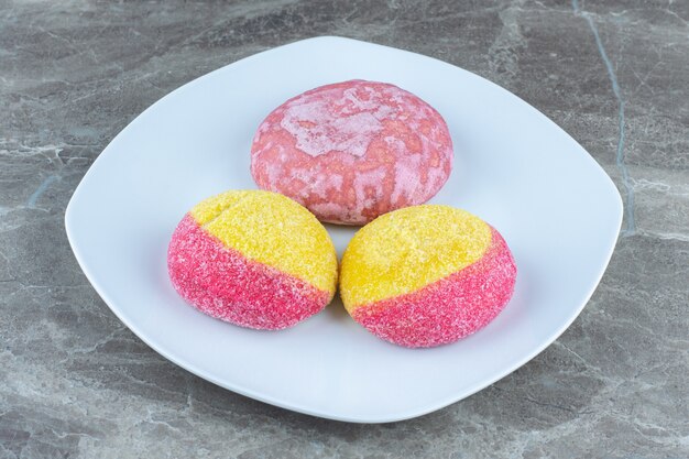 Galletas en forma de melocotón y galleta rosa sobre placa blanca. Cerca de la foto.