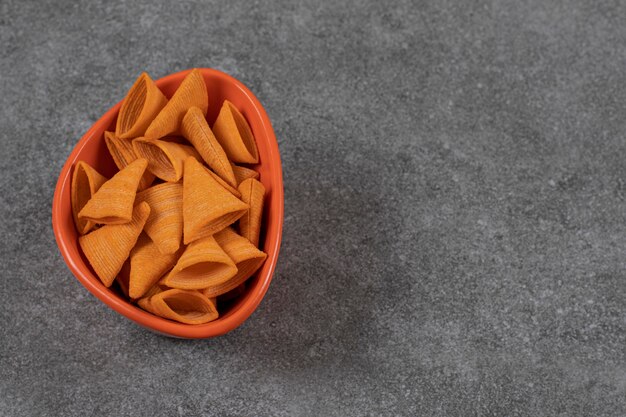 Galletas en forma de triángulo en tazón de fuente naranja.