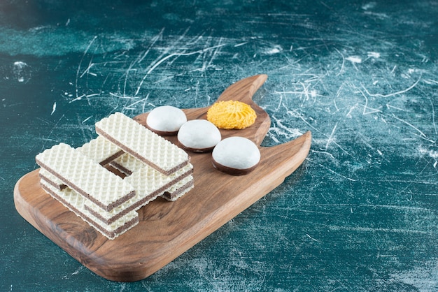 Galletas y gofres crujientes de vainilla sobre tabla de madera.