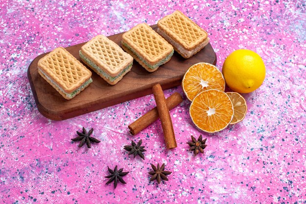 Galletas de gofres de media vista superior con relleno de crema de frutas sobre fondo rosa claro.