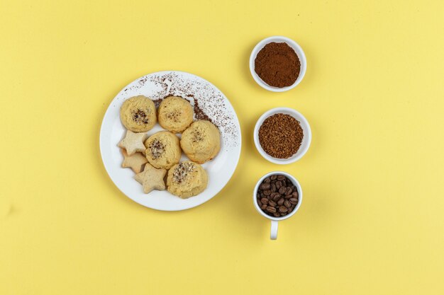 Galletas y granos de café sobre un fondo amarillo