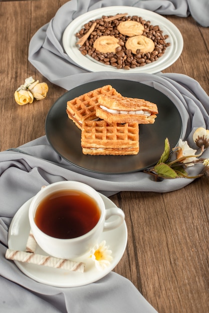 Galletas en granos de café con waffler en un plato y una taza de té.