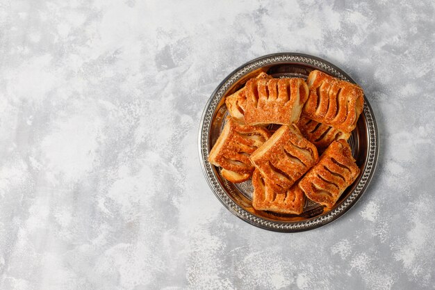 Galletas de hojaldre rellenas de mermelada de manzana y manzanas rojas frescas sobre hormigón ligero