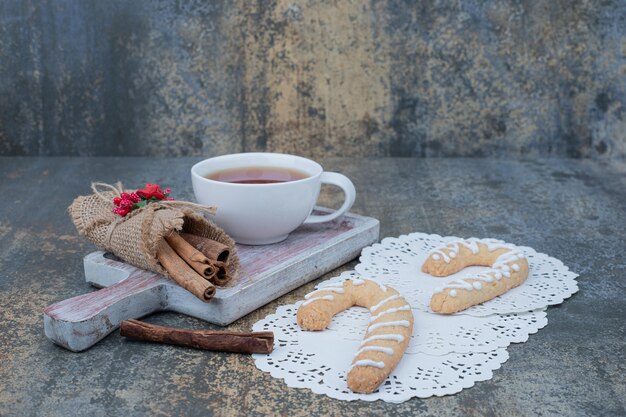 Galletas de jengibre, canela y taza de té en la mesa de mármol. Foto de alta calidad