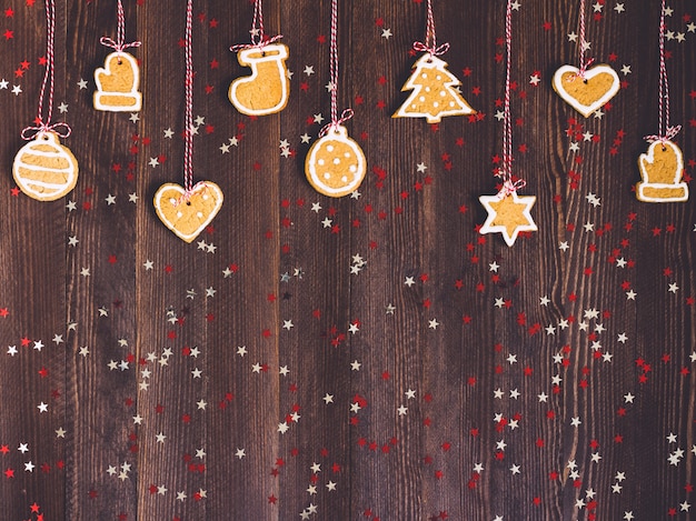 Galletas de jengibre en cuerda para año nuevo de decoración de árbol de navidad en mesa de madera