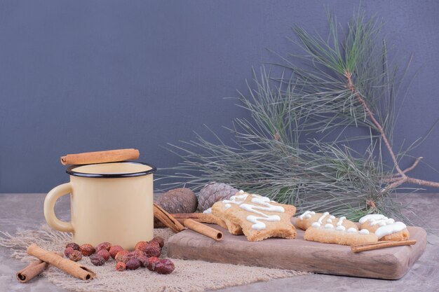 Galletas de jengibre en forma de estrella y oval con canela y una taza de leche.