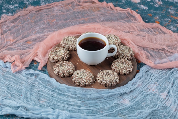 Galletas de jengibre y sésamo en un plato de madera.