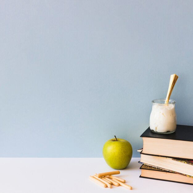 Galletas y manzana cerca de libros y yogur