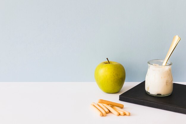 Galletas y manzana cerca de yogur y cuaderno