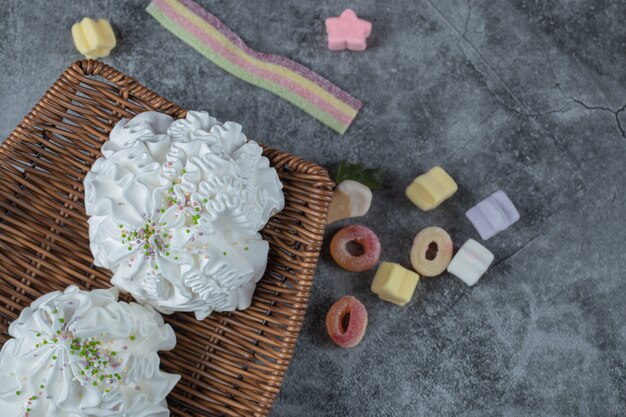 Foto gratuita galletas de merengue blanco en bandeja de madera con gominolas alrededor.