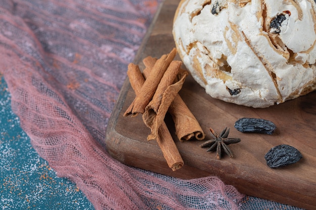 Galletas de merengue blanco con pasas negras sobre una tabla de madera.