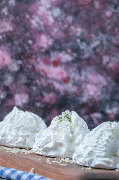 Galletas de merengue blanco sobre una tabla de madera con coco en polvo en la parte superior.