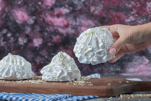 Foto gratuita galletas de merengue floral blanco con coco en polvo sobre una tabla de madera.