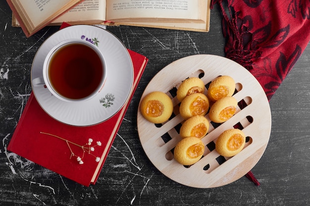 Galletas con mermelada de naranja servidas con una taza de té, vista superior.