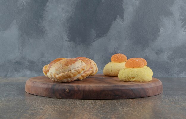 Galletas, mermeladas y bollos pequeños en una tabla