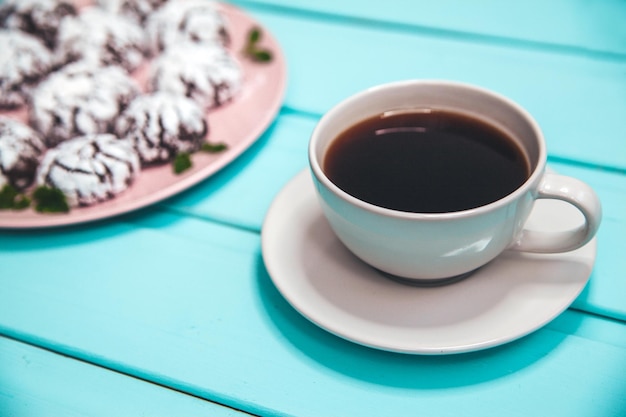 Galletas en una mesa de madera azul en un plato con una taza de café