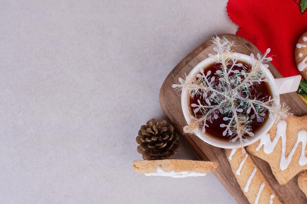 Galletas de Navidad con aroma de té en taza sobre mesa blanca.