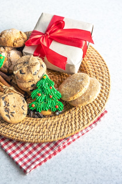 Foto gratuita galletas navideñas festivas y caja de regalos en un plato de mimbre en la mesa de la cocina