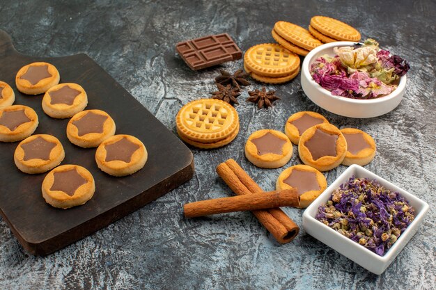 Galletas o bandeja de madera con ramas de canela y flores secas en gris